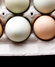 Egg carton with mix of white and brown eggs on a table next to three eggs