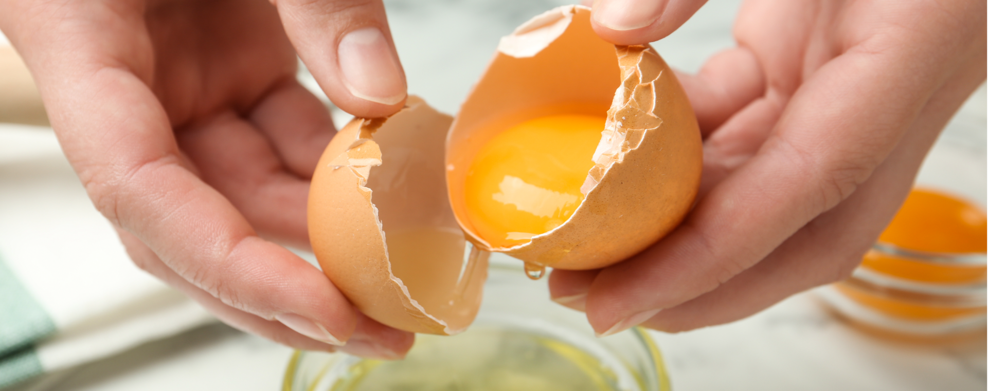 Woman separating egg whites from an egg into a glass mixing bowl