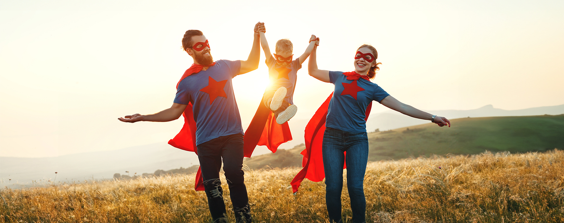 Family dressed as superheroes lifting child in the middle