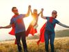 Family dressed as superheroes lifting child in the middle